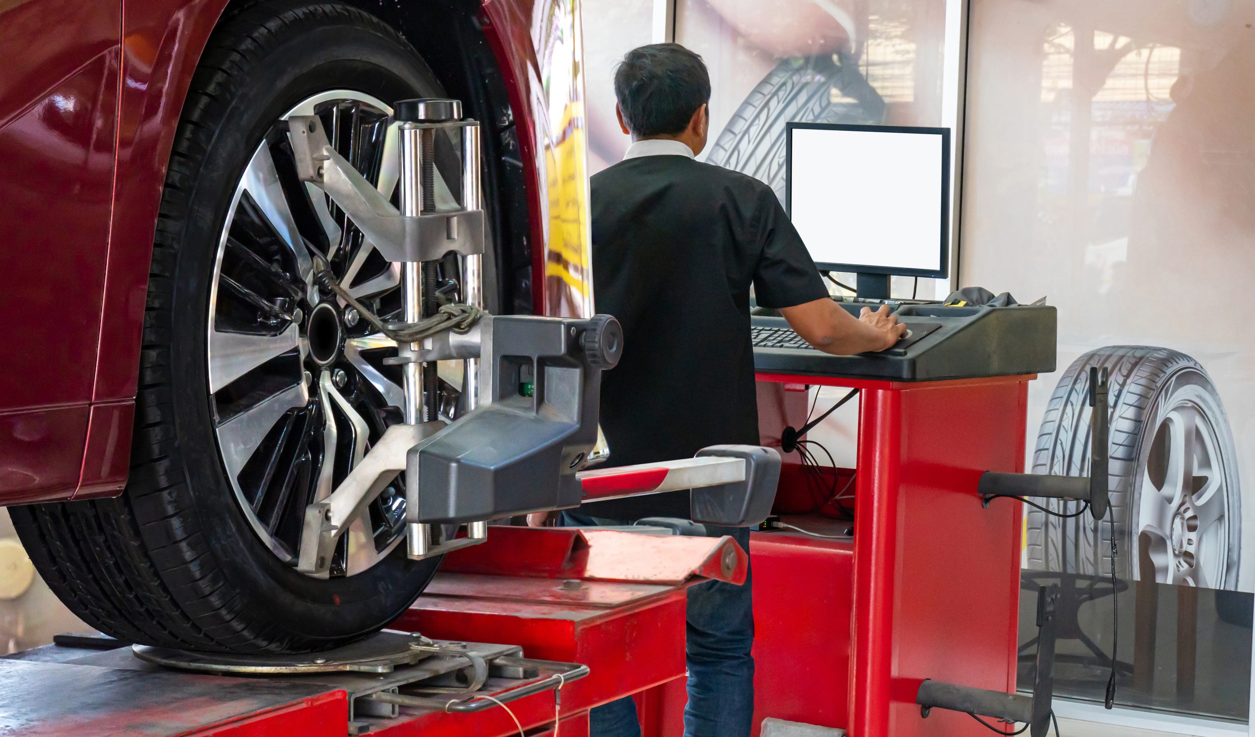 A photo of a car tire and a tech checking a computer.