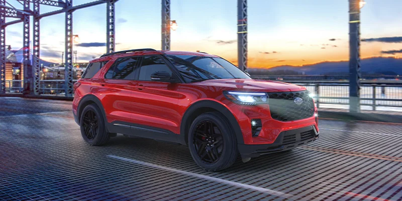 A photo of a red 2025 Ford Explorer driving on a bridge.